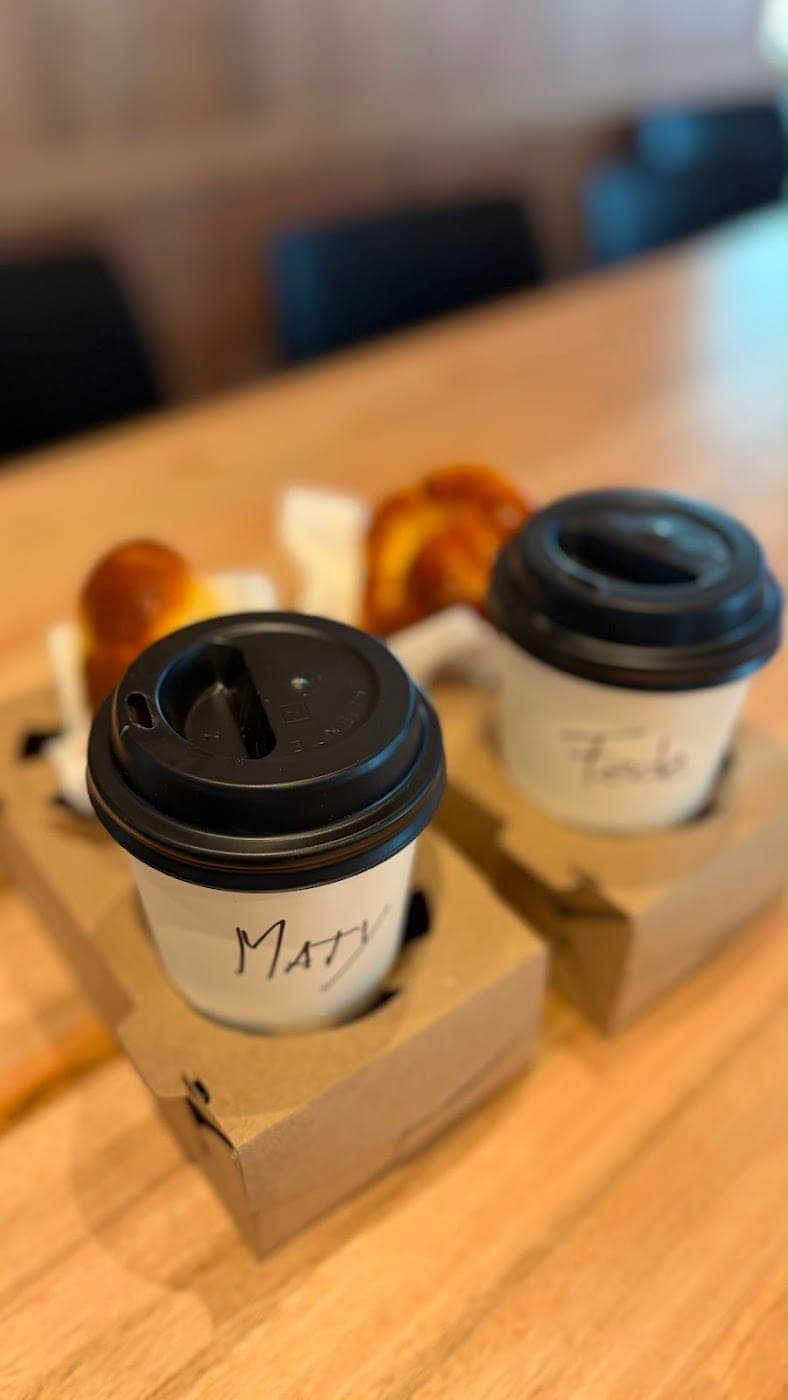 Dos cafés listos para llevar, con el nombre escrito
